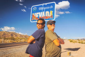 Making Memories 1 Portrait of David and Gio Skelton making memories under the Welcome to Nevada sign at the California and Nevada Stateline in Nipton, CA