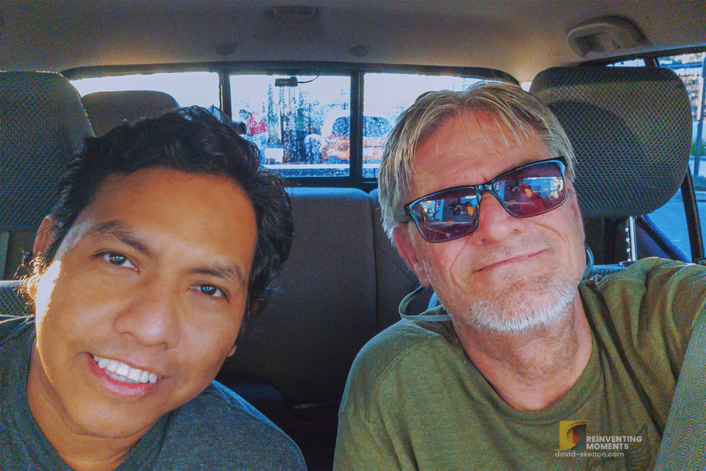 About Me 8 Selfie of David and Gio in a Nissan Frontier at GO Car Wash, Highland, CA, with seatbelts on, ready for a truck cleaning adventure.