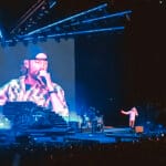 Dierks Bentley performing live on stage at the North Island Credit Union Amphitheater during his 2021 "Beers on Me" Tour, with his image projected on a large video screen.