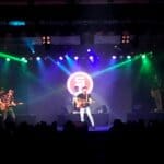 Scotty McCreery singing and playing guitar center stage at Morongo Casino, bathed in blue and green concert lighting.