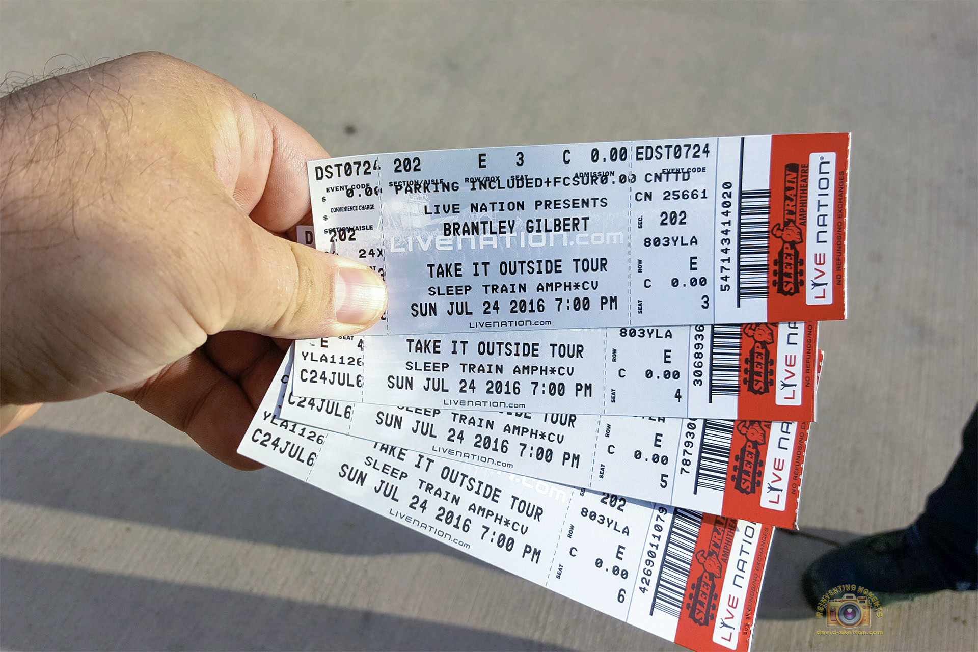 A hand holding four fanned-out Live Nation tickets for a Brantley Gilbert concert at the Sleep Train Amphitheatre on July 24, 2016.