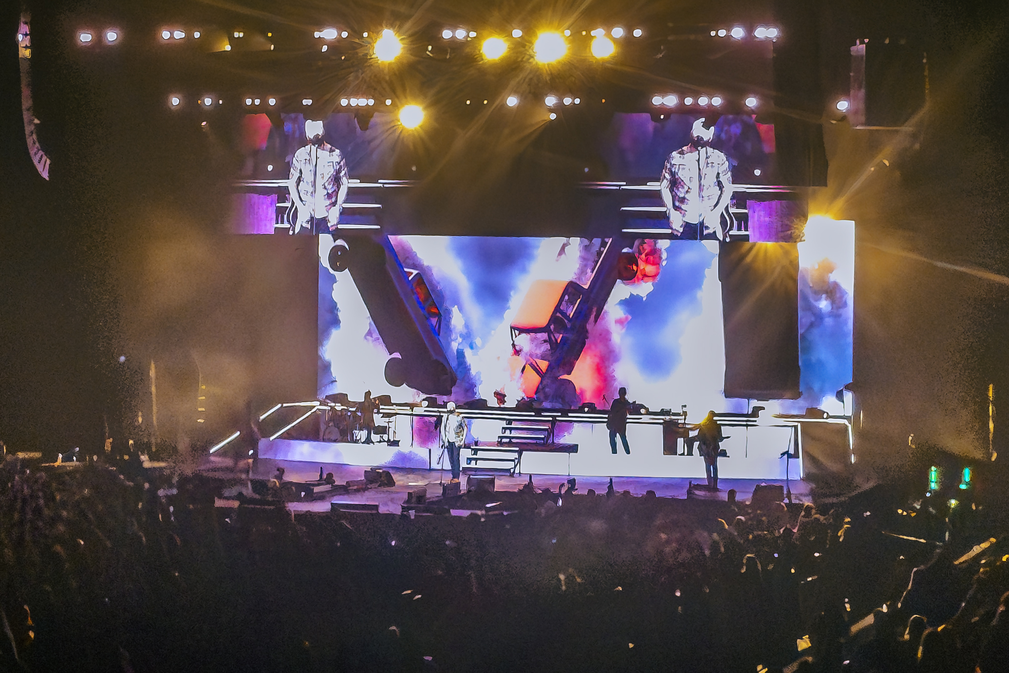 From the crowd, a wide shot of country artist Jordan Davis performing on a brightly lit stage with large video screens and dramatic lighting at the Acrisure Arena.
