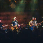 Chris Lucas and Preston Brust of the country band LoCash sing and play acoustic guitars under warm, hazy stage lights during a live concert at the House of Blues in Anaheim.