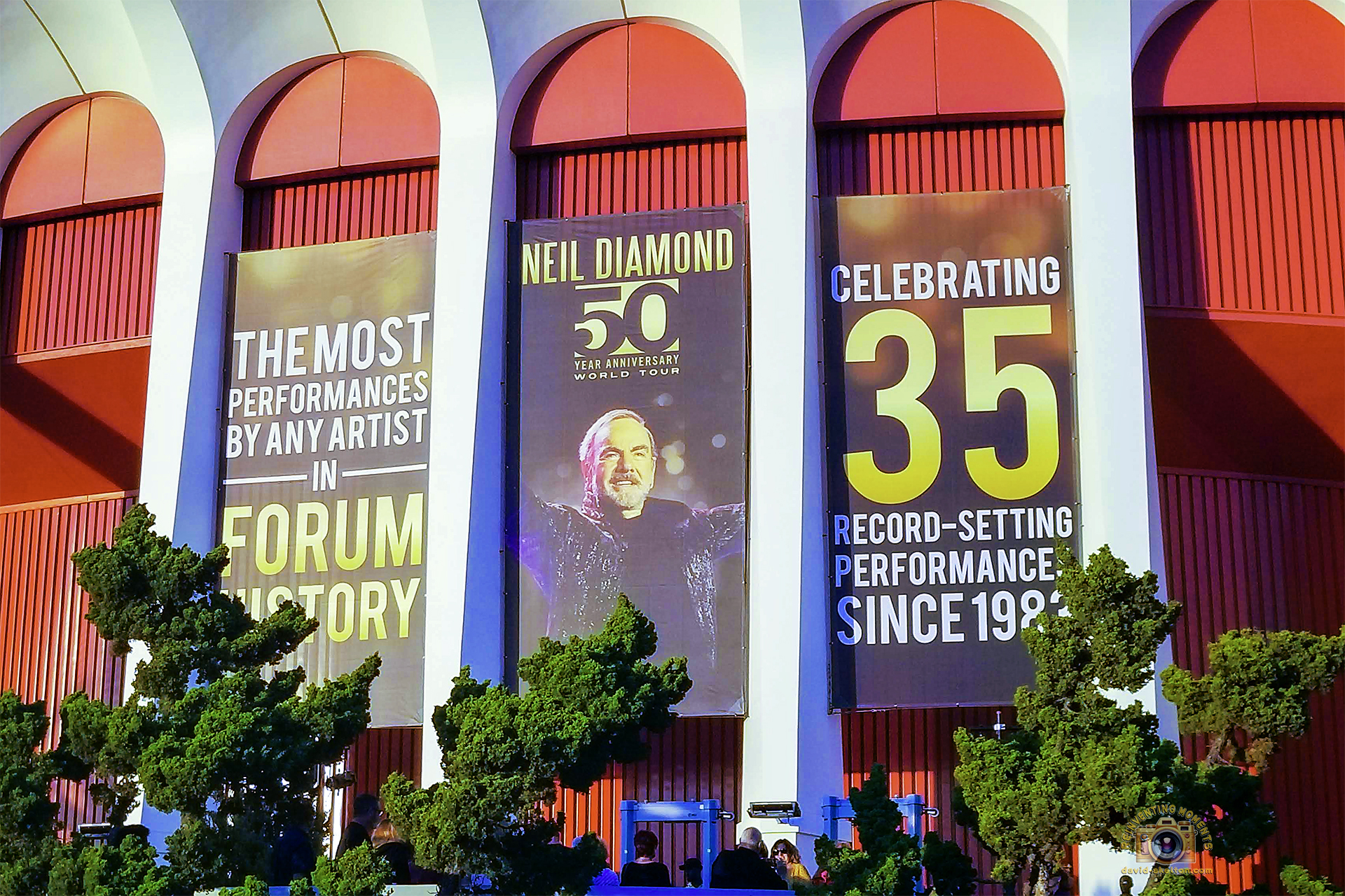 The red-arched exterior of The Forum in Inglewood, decorated with large banners for the Neil Diamond 50 Year Anniversary World Tour, celebrating 35 record-setting performances.