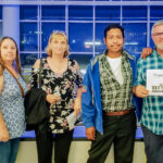 Four people, including me and my husband, Gio, standing in the glass concourse of STAPLES Center, Los Angeles, holding a "Thank You VET TIX" sign, before the Keith Urban Graffiti U Tour concert
