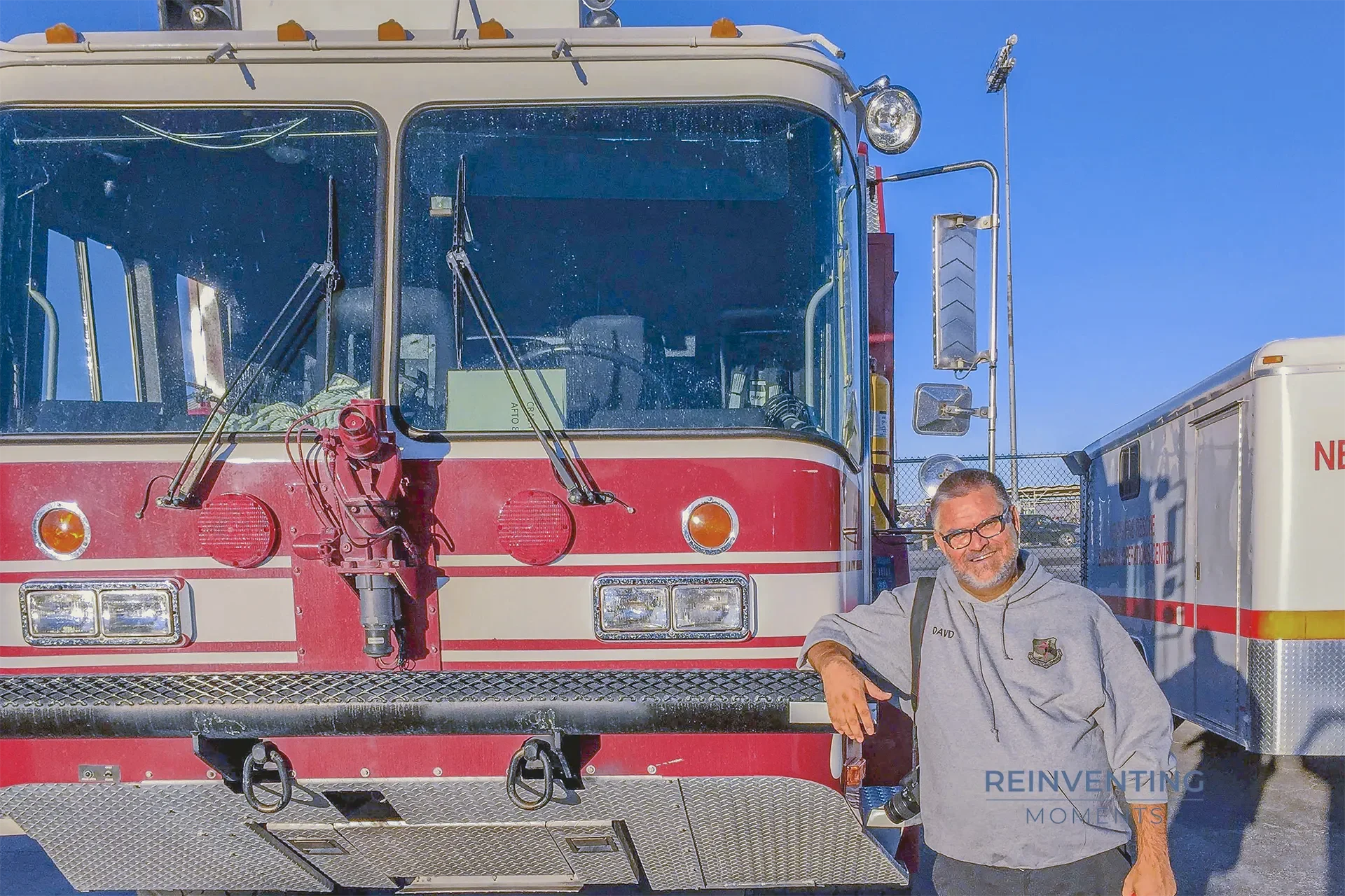 Air Force veteran David Skelton smiling next to a red and white Oshkosh P-19 aircraft rescue and firefighting (ARFF) crash truck at Nellis Air Force Base.